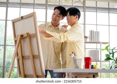 Couple gay or lgbt man enjoy to draw and paint a picture together at home in living room with glass window and day light happy time.