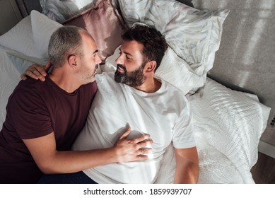 Couple Of Gay Men Together In Bed At Home Lying On The Mattress And Looking At Each Other's Faces