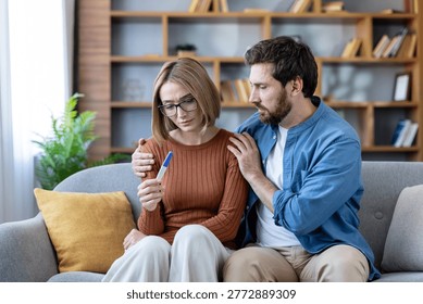Couple getting devastating news from a negative at-home pregnancy test, a man comforting his sad wife experiencing infertility issues and disappointment while trying to conceive