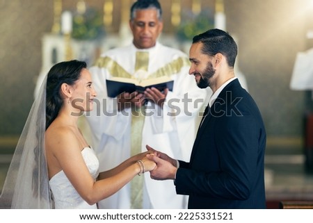 Couple getting married, wedding vows and love commitment at the alter of church during marriage ceremony. Happy bride, groom and Christian priest performing rites, religious and spiritual connection