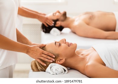 Couple Getting Relaxing Head Massage Together Lying On Beds With Eyes Closed Indoors. Wellness, Acupressure Therapy And Relaxation Concept. Beauty Day At Spa. Selective Focus