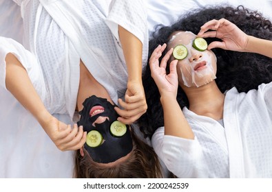Couple of girlfriend in bathrobe doing skincare routine using facial mask and cucumber slice on spa holiday for beauty skin and treatment