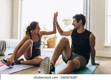 Couple Giving Each Other High Five After A Successful Workout Together. Man And Woman In Sports Wear Doing Workout In Living Room.