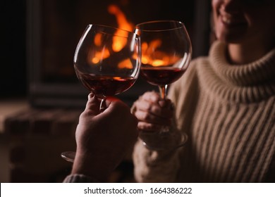 Couple with glasses of red wine near fireplace, closeup - Powered by Shutterstock