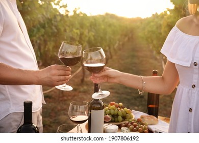 Couple with glasses of wine in vineyard on sunny day, closeup - Powered by Shutterstock