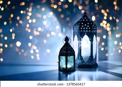Couple of glowing Moroccan ornamental lanterns on the table. Greeting card, invitation for Muslim holy month Ramadan Kareem. Festive blue night background with glittering golden bokeh lights. - Shutterstock ID 1378565417