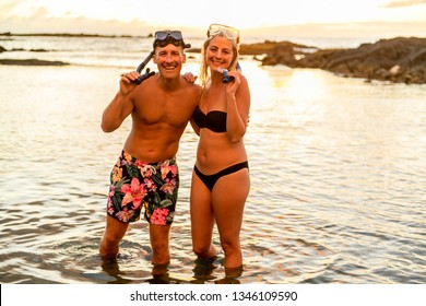 Couple Is Going To Swim And Snorkle On Hawaii Beach At The Sunset