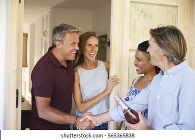 Couple Greeting Their Guests At The Door Of Their Home