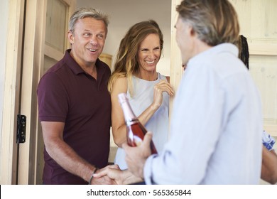 Couple Greeting Their Guests At The Door Of Their Home