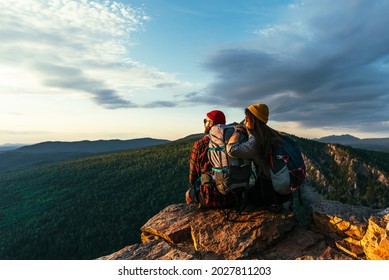 The couple greets the sunrise in the mountains. A man and a woman in the mountains. Wedding travel. Honeymoon trip. A couple of travelers in love. People greet the dawn. Lovers travel. Copy space