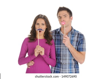 Couple Grimacing. Beautiful Young Couple Holding The Fake Moustache And Lips On Stick  While Isolated On White