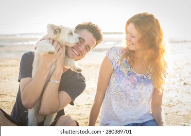 Couple Of Guys Playing With Their Dog On The Beach