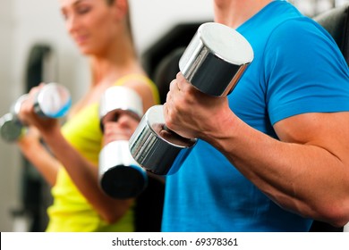 couple in the gym, rivaling each other, exercising with dumbbells