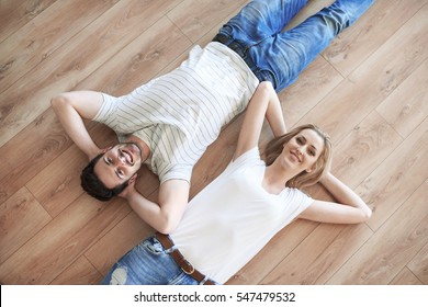 Couple with hands behind head laying on the floor