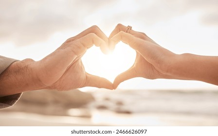 Couple, hands and heart by sunset with love on beach for honeymoon or vacation in summer with romantic gesture. Commitment, partnership and marriage with trust, promise and together in the Maldives. - Powered by Shutterstock