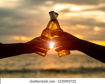 Couple hands holding beer bottles and clanging on the sunset beach. Party, Holiday, Summer, Friendship Concept. - Shutterstock ID 1135992722