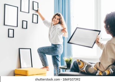 Couple Hanging Picture Frame On Wall In New House