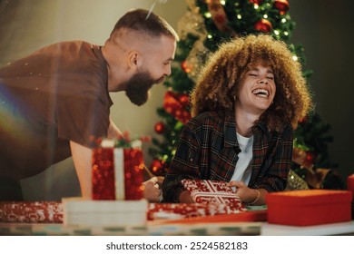 Couple happily wraps christmas presents together at a cozy table. Surrounded by festive decorations and twinkling lights. Sharing laughter and love as they prepare surprises for family and friends - Powered by Shutterstock