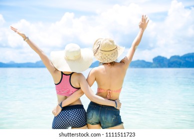 Couple of happy lovely friends wearing bikini , standing back side and open arms on the beach,enjoying summer vacation Summer joy concept and multiethnic friendship