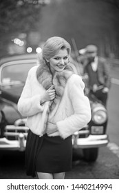 Couple Happy At Vintage Retro Car. Friends On Winter Road Trip In Black Car. Beautiful Young Caucasian Man And Sexy Woman Smiling Joyful In Fur Coat