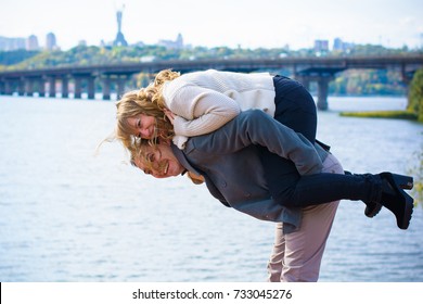 Couple Has Fun And Laughs. Kiss. Middle Aged Couple Hugging Each Other In Autumn Park. Spring Or Winter Love Story, A Beautiful Stylish Couple At City. Winter Fashion Concept With Men And Woman