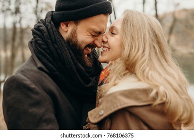 Couple Has Fun And Laughs. Kiss. Young Hipster Couple Hugging Each Other In Winter Park. Winter Love Story, A Beautiful Stylish Young Couple. Winter Fashion Concept With Boyfriend And Girlfriend.