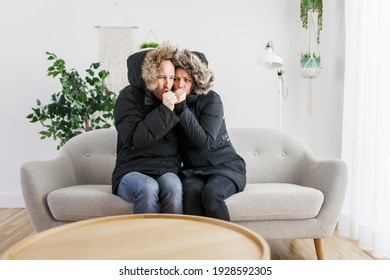 A Couple have cold on the sofa at home with winter coat