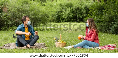 Couple have date during the coronavirus lockdown crisis. Man and woman in the park. Social distancing and virus protection.