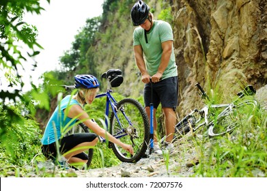 Couple Have A Flat Tyre With Mountain Bike Outdoor In The Wilderness