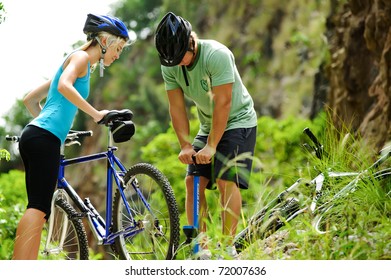 Couple Have A Flat Tyre With Mountain Bike Outdoor In The Wilderness