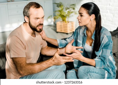 Couple Having Argument And Wife Trying To Calm Down Angry Husband At Home