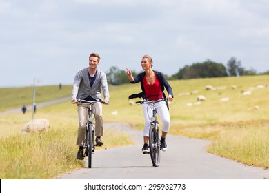 Couple Having Bicycle Tour With Bike At Levee With Sheep