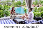 couple having a coconut drink and cocktail by the pool in Pattaya Thailand, men and woman on a beach bed in a cabana