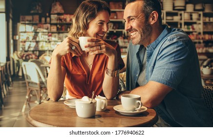 Couple having coffee at a coffee shop. Man and woman meeting at cafe. - Powered by Shutterstock