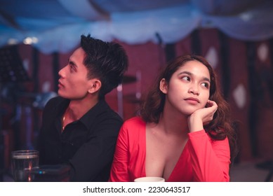 A couple having a date at an elegant restaurant sits back to back and ignores each other as they are having an argument. A lady is upset with her insensitive boyfriend. Waiting for the night to end. - Shutterstock ID 2230643517