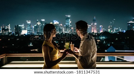couple having a drink on roof terrace overlooking the city skyline