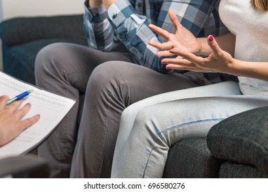 Couple having fight in therapy or marriage counseling. Man and woman sitting on couch. Wife waving hands. Session with psychologist, counselor, therapist, psychiatrist or relationship consultant.