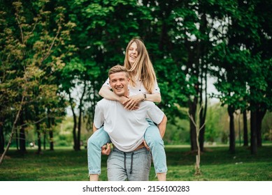 The couple is having fun in the park. girl on guy's back