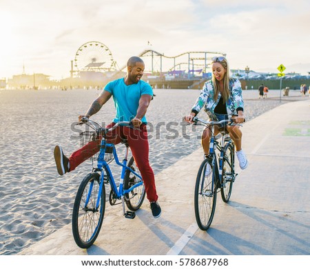couple having fun riding bikes together at santa monica california