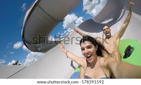 Couple having fun and sliding down in a water slide