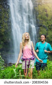 Couple Having Fun Together Outdoors On Hike To Amazing Waterfall In Hawaii.