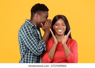 Couple Having Fun While Sharing a Secret in Front of a Yellow Background