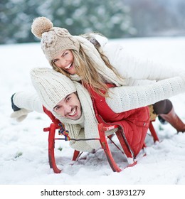 Couple Having Fun While Sledding On Sled In Winter