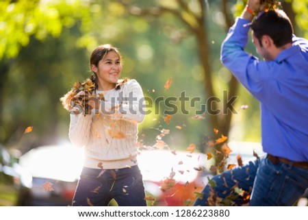 Couple having a play fight with autumn leaves
