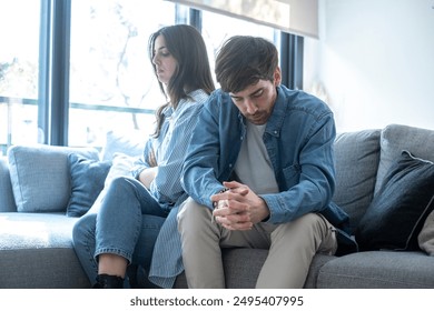 Couple having problems in relationship break up moment sad at home sitting on the couch ignoring in silence. Bad moment in marriage with sad man and upset woman. Financial difficulties people inside