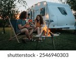 Couple having romantic picnic during camping trip in nature, eating watermelon. Caravan traveling for young people.