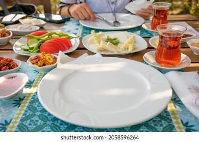 Couple Having Turkish Style Breakfast On Wooden Table. Happy Family Having Breakfast, Good Time. Selective Focus. Tasty Olives, Fresh Cucumbers, Jams, Tomato Sauces, Cheeses, Turkish Tea, Peppers. 