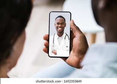 Couple Having Video Chat With Doctor On Mobile Phone At Home