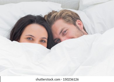 Couple Hiding Under The Duvet In Their Bed