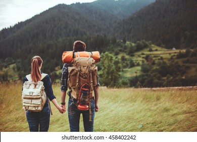 A couple hikers Hiking with backpacks walk along a beautiful mountain area holding hands . The concept of active rest - Powered by Shutterstock